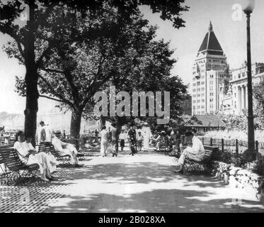 Cina: Seduti e passeggiando sul Bund di Shanghai (Waitan) in una giornata illuminata dal sole intorno al 1935. Il Cathay Hotel sullo sfondo. Il Bund (cinese: Wàitān) è un'area del distretto di Huangpu nel centro di Shanghai. L'area si concentra su una sezione di Zhongshan Road (East-1 Zhongshan Road) all'interno dell'ex insediamento internazionale di Shanghai, che corre lungo la riva occidentale del fiume Huangpu, di fronte a Pudong, nella parte orientale del distretto di Huangpu. Il Bund di solito si riferisce agli edifici e ai moli su questa sezione della strada, così come ad alcune aree adiacenti. Foto Stock