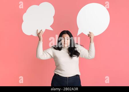 Scelta difficile. Interessata donna che tiene due bolle vuote del discorso Foto Stock