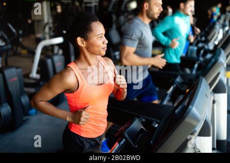 Gruppo di giovani che corrono su tapis roulant in palestra sportiva Foto Stock