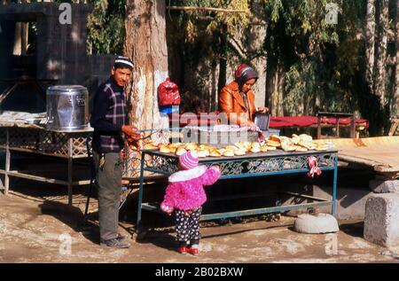 Cina: Venditore di pane in una piccola città oasi vicino a Khotan, provincia dello Xinjiang. Dalla covata olandese, dal brot tedesco e dalla brea frisone, il pane inglese antico è un tipo di cibo popolare in tutto il mondo e vecchio come la civiltà organizzata. È il cibo di base in Europa e nelle culture influenzate dall'Europa nelle Americhe, in Africa e in Medio Oriente, in contrasto con l'importanza del riso nell'est e nel sud-est asiatico. Khotan traccia la sua storia almeno fino al III secolo a.C., quando si dice che il figlio maggiore dell'imperatore indiano Asoka si sia insediato qui. Foto Stock