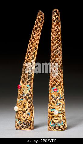 Le descrizioni occidentali degli imperatori cinesi, dei re e dei nobili spesso menzionano le unghie abbastanza lunghe da marcare la persona sopra ogni possibilità di lavoro manuale. Queste protezioni per unghie, o protezioni, potrebbero essere indossate come un unico gioiello sulla mano o in più set. Secondo il Museo d'Arte di San Diego: 'I protettori delle unghie sono stati indossati da un gruppo molto d'elite - le Signore corte di Manchu della tarda dinastia Qing. Sebbene gli studiosi di costumi cinesi di solito datano protettori delle unghie alla dinastia Qing, essi sono infatti caratteristici solo della fine del 19th secolo. Ritratti di prime Signore della corte di Qing Foto Stock