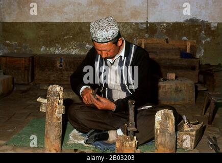 La piccola oasi dominata dagli uiguri di Yengisar (Yingjisha) è conosciuta in tutta la provincia cinese occidentale dello Xinjiang per la produzione di coltelli fatti a mano. La fabbrica di coltelli piccoli (Pichak Chilik Karakhana / Xiaochang) impiega abili artigiani locali che producono coltelli sottili con manici intarsiati. Appena circa ogni uomo di Uighur porta un coltello, sia come segno di manhood che per lo scopo più utilitaristico di tagliare i meloni ed il più stimato (e costoso) viene da Yengisar. Foto Stock