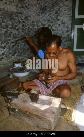 Sul bordo orientale dell'Atollo di Nilandhoo Sud si trova la piccola isola di Rinbudhoo. Qui, in uno dei villaggi più tranquilli e puliti delle Maldive, vive l'unico gruppo di orafi ereditari del paese. Fondendo sovrani d'oro vittoriani e thaler Marie-Therèse come casualmente come piccoli lingotti importati di recente da Dubai, essi producono una squisita gamma di catene, collane, orecchini, anelli di dita e amuleti. La nazione più piccola e meno conosciuta dell'Asia, la Repubblica delle Maldive, si trova disseminata da nord a sud attraverso un'apertura di 750 chilometri dell'Oceano Indiano a 500 chilometri a sud di wes Foto Stock