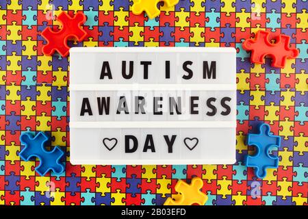 Light box con testo del giorno di consapevolezza dell'autismo mondiale su sfondo puzzle colorato. Vista dall'alto Foto Stock