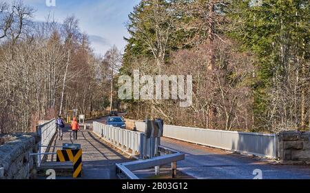 CARRON VILLAGE MORAY SCOZIA ESCURSIONISTI E AUTO SULLA STRADA UNICA CARRON E VECCHIO PONTE FERROVIARIO CHE ATTRAVERSA IL FIUME SPEY Foto Stock