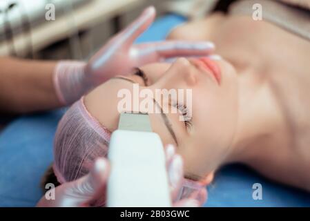 La cura della pelle. Close-up di bella donna ricevendo ultrasuoni cavitazione peeling del viso. Ultrasuoni Detersione della pelle procedura. Trattamenti di bellezza Foto Stock