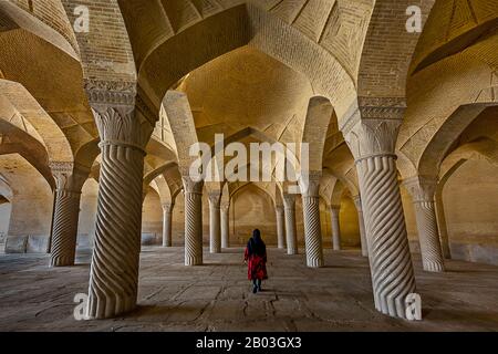 La Moschea Vakil con una donna iraniana in abito rosso sotto i suoi archi, di Shiraz, Iran Foto Stock