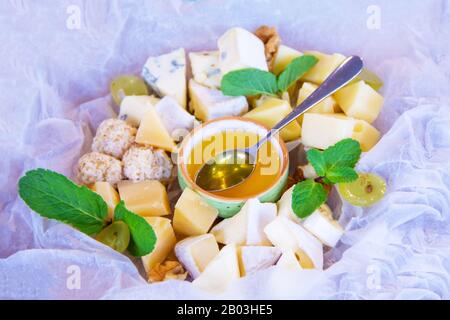 Molti tipi di formaggio Parmigiano, Gouda, Emmental formaggio con miele, noci e physalis. Antipasto in un ristorante francese, spuntino per vino. Piatto per Foto Stock