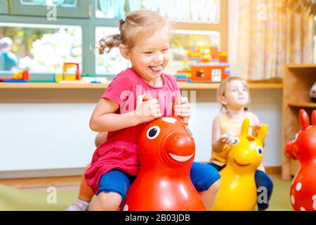 Bambine equitazione nel riprodurre i cavalli in kindergarten Foto Stock