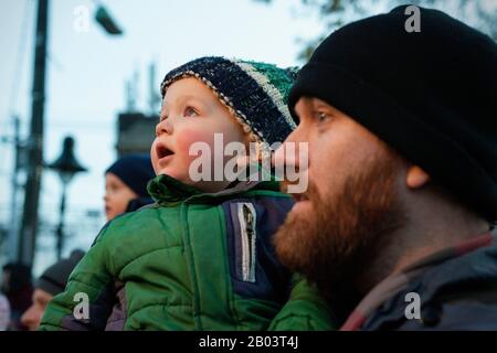 Un padre e un figlio che guardano l'illuminazione dell'albero di Natale. Foto Stock