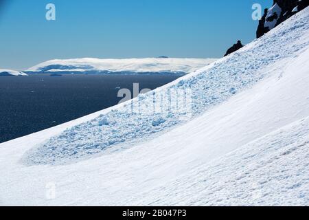 Detriti di valanghe al porto di Orne sulla costa di Danco, Graham Land, Antartide. Foto Stock