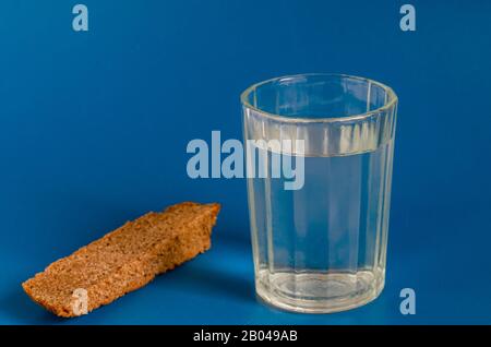 Vetro sfaccettato di forte alcol e pane su sfondo blu. Primo piano. Messa a fuoco selettiva. Foto Stock