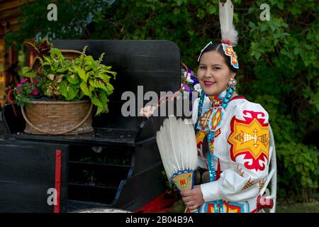 Giovane Salish donna (versione modello 20140213) in un abito jingle con un fan di piume d'aquila al Flathead Lake Lodge di Averill, un ranch dude vicino Kalispell, Foto Stock