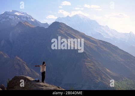 Uomo con camicia bianca sulla cima di una montagna a Hunza, Paksitan - Trekking sul tetto del mondo - Foto Stock