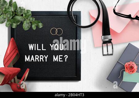lettera bordo con testo di proposta 'mi sposerete?' circondato da oggetti diversi Foto Stock
