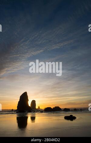 Le pile di mare si silhouette al tramonto durante la bassa marea a Cannon Beach sulla costa settentrionale dell'Oregon, Stati Uniti. Foto Stock