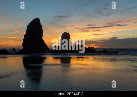 Le pile di mare si silhouette al tramonto durante la bassa marea a Cannon Beach sulla costa settentrionale dell'Oregon, Stati Uniti. Foto Stock