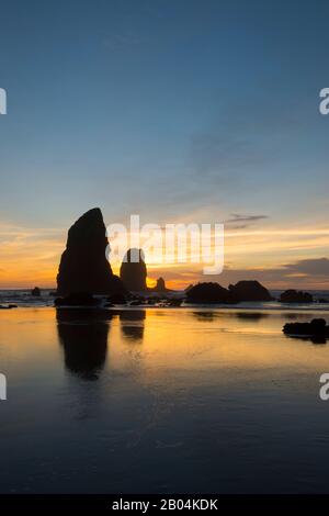 Le pile di mare si silhouette al tramonto durante la bassa marea a Cannon Beach sulla costa settentrionale dell'Oregon, Stati Uniti. Foto Stock