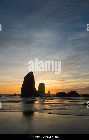 Le pile di mare si silhouette al tramonto durante la bassa marea a Cannon Beach sulla costa settentrionale dell'Oregon, Stati Uniti. Foto Stock