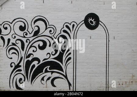un design nero su una parete esterna di mattoni dipinta di bianco Foto Stock