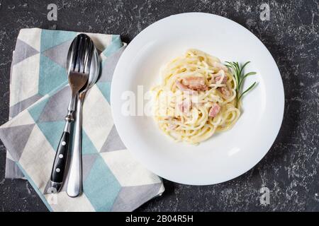 Pasta carbonara servita su piatto profondo decorato con rosmarino. Vista dall'alto Foto Stock