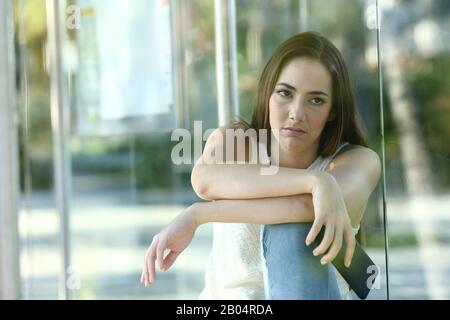 Ritratto della vista frontale di una donna annoiata in attesa di un trasporto ritardato in una fermata dell'autobus Foto Stock