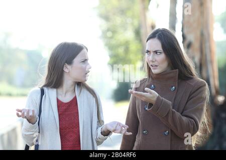 Ritratto di fronte di due donne arrabbiate che litigano in un parco in inverno Foto Stock