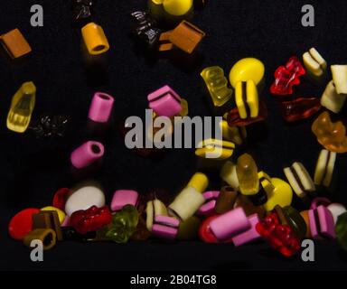 Molti dolci e colorati caramelle stanno cadendo giù ad un tavolo nero Foto Stock