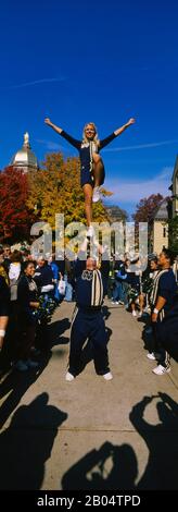 Donna in piedi una gamba su una mano d'uomo e che esegue una stunt, University Of Notre Dame, South Bend, Indiana, USA Foto Stock