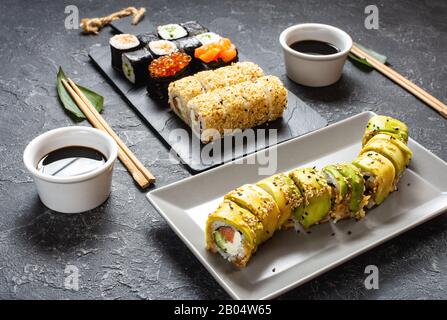 Vari tipi di sushi servita sulla pietra nera dello sfondo. Foto Stock