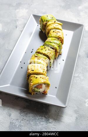 Drago verde sushi rotolo con anguilla, avocado, cetriolo su tavolo in cemento. Tradizionale riso asiatico sano frutti di mare. Foto Stock