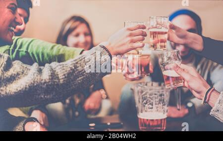 Amici felici tostare birre e ridere in chalet pub in montagna - giovani divertirsi in vacanza invernale - concetto di amicizia - Focus sulla sinistra Foto Stock
