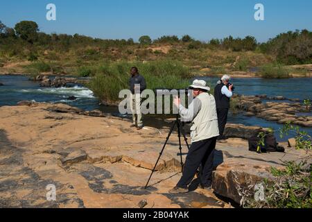 Turisti che fotografano sulla riva del fiume Sabie nella Sabi Sands Game Reserve adiacente al Kruger National Park in Sud Africa. Foto Stock