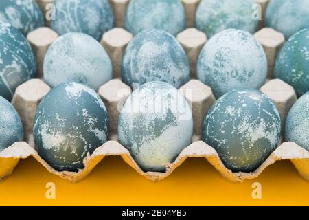 Le uova di Pasqua di colore blu testurizzato su uno sfondo giallo brillante per le vacanze. Concetto di vacanza primaverile. Copyspace. Disposizione piatta. Vista dall'alto Foto Stock