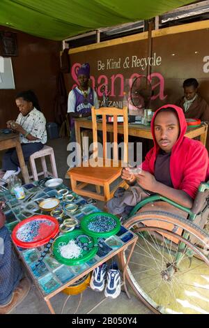 Persone disabili locali che fanno artigianato utilizzando materiali riciclati per il mercato all'ingrosso e al dettaglio dei consumatori presso la Shanga House di Arusha, in Tanzania Foto Stock