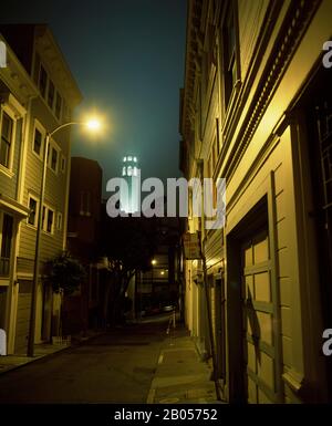 Edifici lungo una strada con una torre sullo sfondo, Coit Tower, San Francisco, San Francisco County, California, Stati Uniti Foto Stock