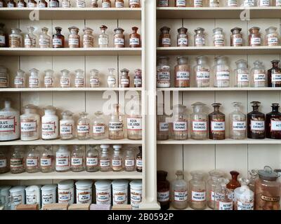 Un primo piano degli scaffali in una vecchia farmacia, bottiglie in vetro con etichetta latina riempite di sostanze chimiche per la preparazione della medicina. Foto Stock