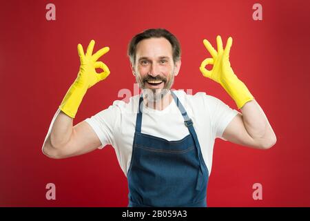 Pulizia eccellente. Ragazzo con bearded che pulisce a casa. Lavoratore con bearded. A protezione della pulizia. Servizio di pulizia e servizio domestico. Molto lavoro. Uomo in grembiule con guanti per la pulizia. Giorno di pulizia oggi. Foto Stock