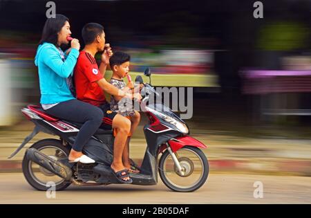 Tre persone sullo stesso motoveicolo succhiando gelato, Thailandia, Phuket Foto Stock