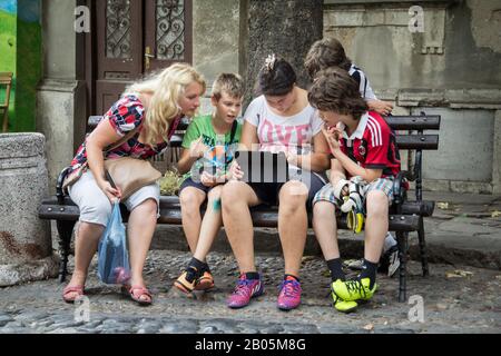 Belgrado, SERBIA - 2 AGOSTO 2015: Famiglia bianca caucasica, madre e figlie e figli, guardando un tablet iPad all'aperto, seduti e navigando Foto Stock