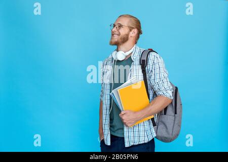 Profilo giovane bearded studente universitario tenere notebook zaino guardare copia spazio Foto Stock