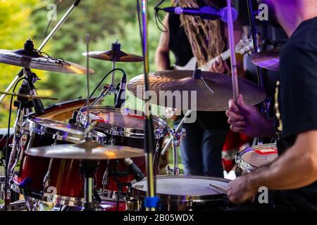 Un primo piano di dettaglio del fuoco selettivo di un uomo che gioca un drum kit sul palco durante un festival che celebra la terra e le comunità alternative Foto Stock