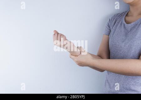 Closeup donna trattiene il suo dolore al polso su sfondo bianco. Medico e sanitario concetto. Foto Stock