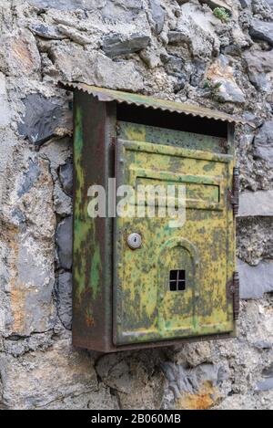 Vecchia casella di posta arrugginita sul muro roccioso nell'antica città italiana Foto Stock