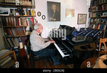 Rostock, Germania. 12th Feb, 2020. Hartwig Eschenburg, musicista di chiesa, suona su un grande pianoforte nel suo appartamento, e un ritratto di Johann-Sebastian Bach si appende sul muro. Il musicista della chiesa riceverà il Premio sociale Siemerling della Neubrandenburg Epiphany Foundation il 24 febbraio 2020. Il premio è dotato di 10.000 euro ed è considerato il più antico premio sociale del nord-est. Credito: Bernd Wüstneck/Dpa-Zentralbild/Dpa/Alamy Live News Foto Stock