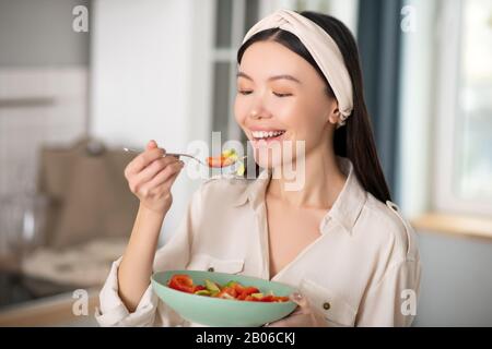 Bella ragazza gioiosa mangiare insalata di verdure. Foto Stock