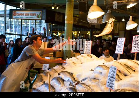 USA, WASHINGTON STATE, SEATTLE, PIKE PLACE MARKET, STAND DI PESCE FRESCO, SPETTACOLO DI PESCE VOLANTE, VENDITORE DI LANCIO DI SALMONE Foto Stock