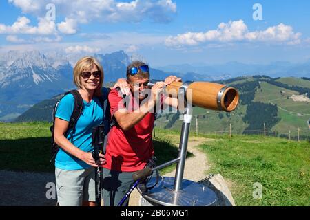 Escursionisti sulla cima percorso panoramico del Salve Hohe guardando attraverso un telescopio, Hopfgarten, Brixental, Alpi Kitzbuehel, Tirolo, Austria Foto Stock