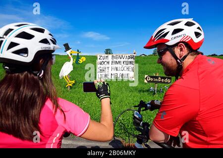 Ciclisti che fotografano cicogne E striscioni Come un benvenuto per un neonato, Seeham, Salisburgo Lakeland, Salzburger Land, Austria Foto Stock