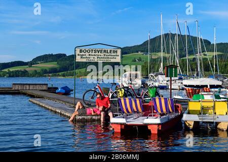 Una coppia di biciclette elettriche fa una pausa in un pontile sul lago Obertromber See, Obertrum, Salzburger Seenland, Salzburger Land, Austria Foto Stock